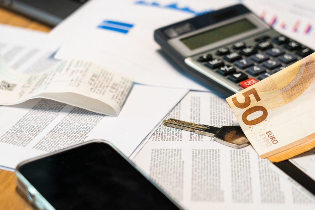 Billets en euros, calculatrice et clé de voiture posés sur une table