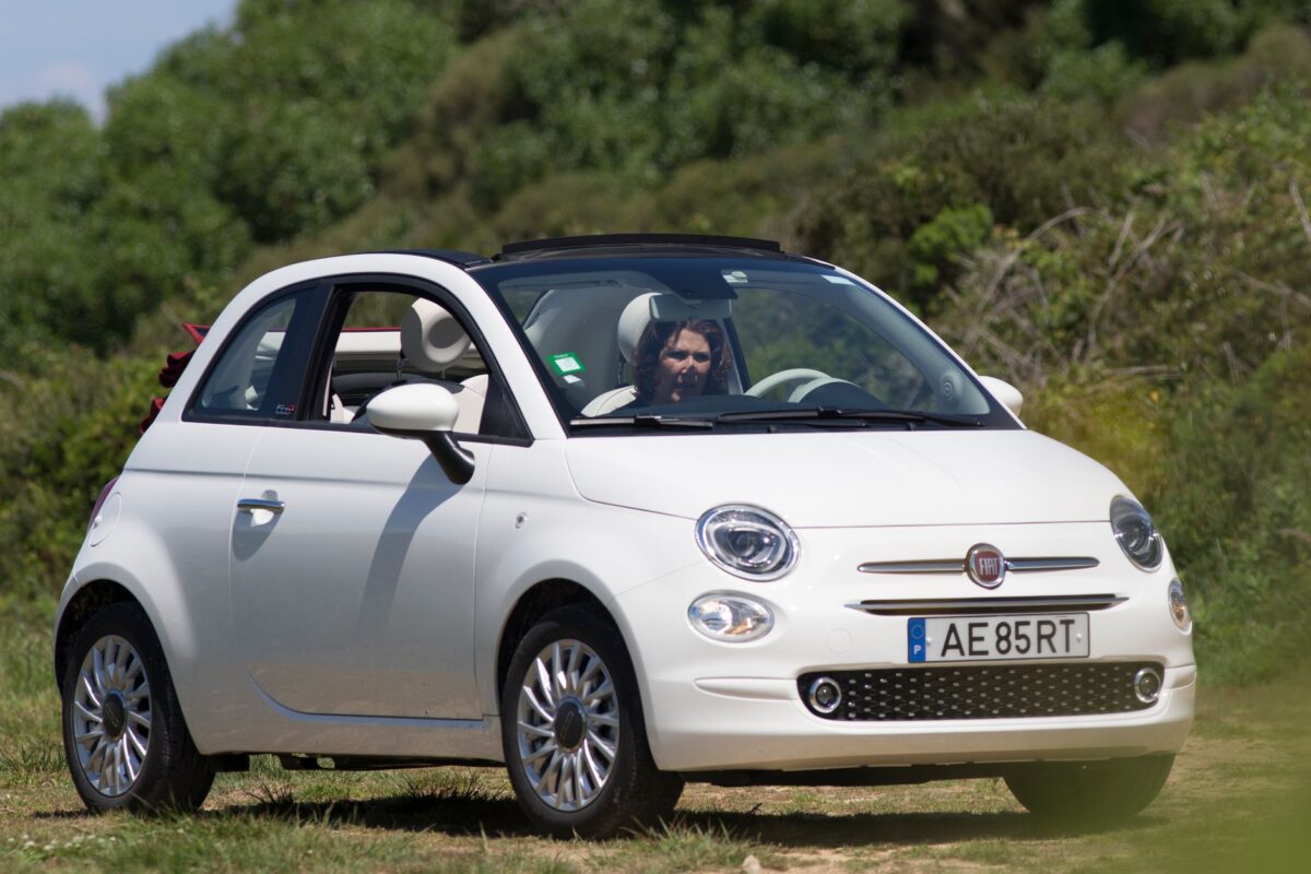 Fiat 500 blanche à toit ouvert sur une route ensoleillée